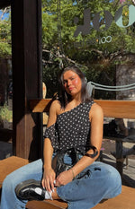 Black polka dot off shoulder top with one shoulder strap and a tie-front waist