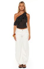 Black polka dot one-shoulder top with a draped ruffle sleeve and cropped hem