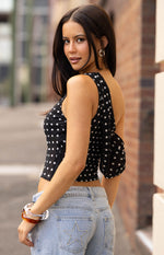 Side view of the black polka dot off-shoulder top with a wide, draped sleeve and fitted cropped bodice