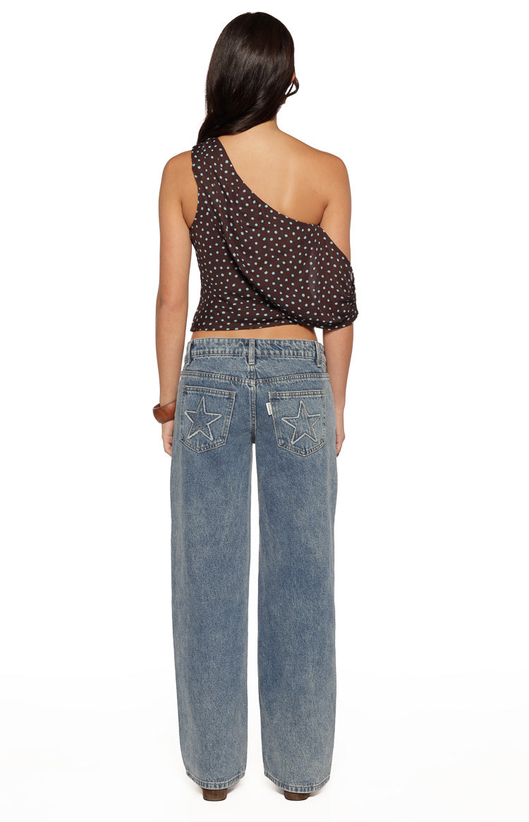 Rear view of a brown off-shoulder top with light blue polka dots and a draped one-shoulder sleeve