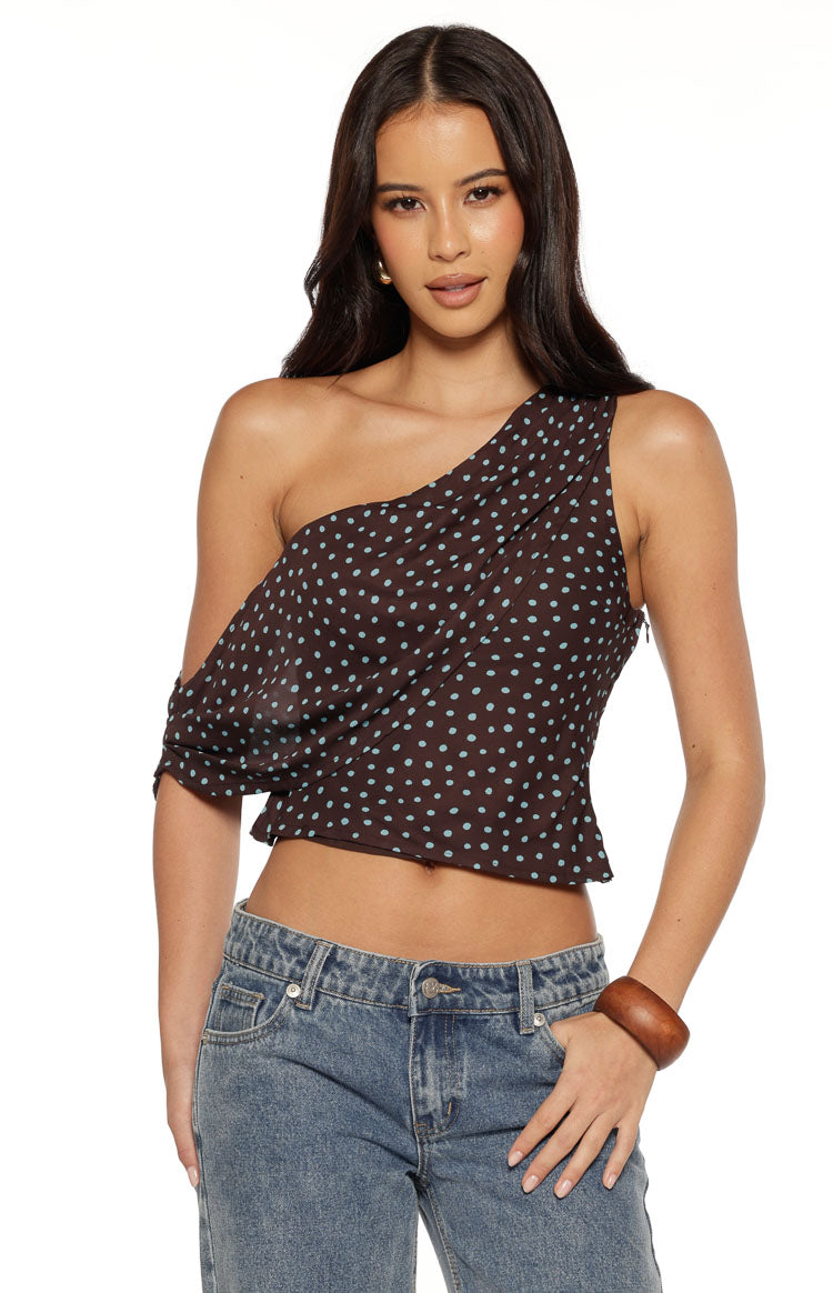 Front view of a brown polka dot one-shoulder top with a draped left sleeve and side zipper