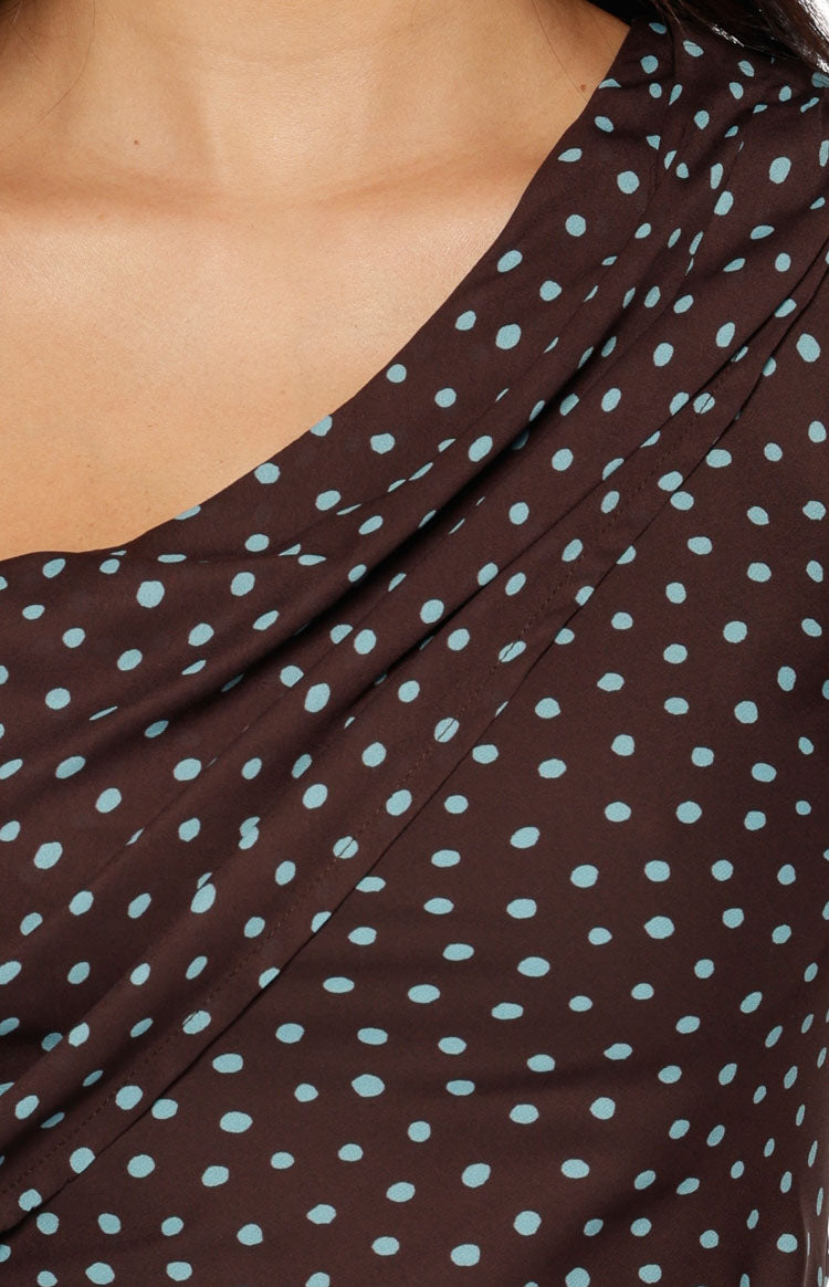 Close-up of the draped brown polka dot fabric showing the off-shoulder neckline detail