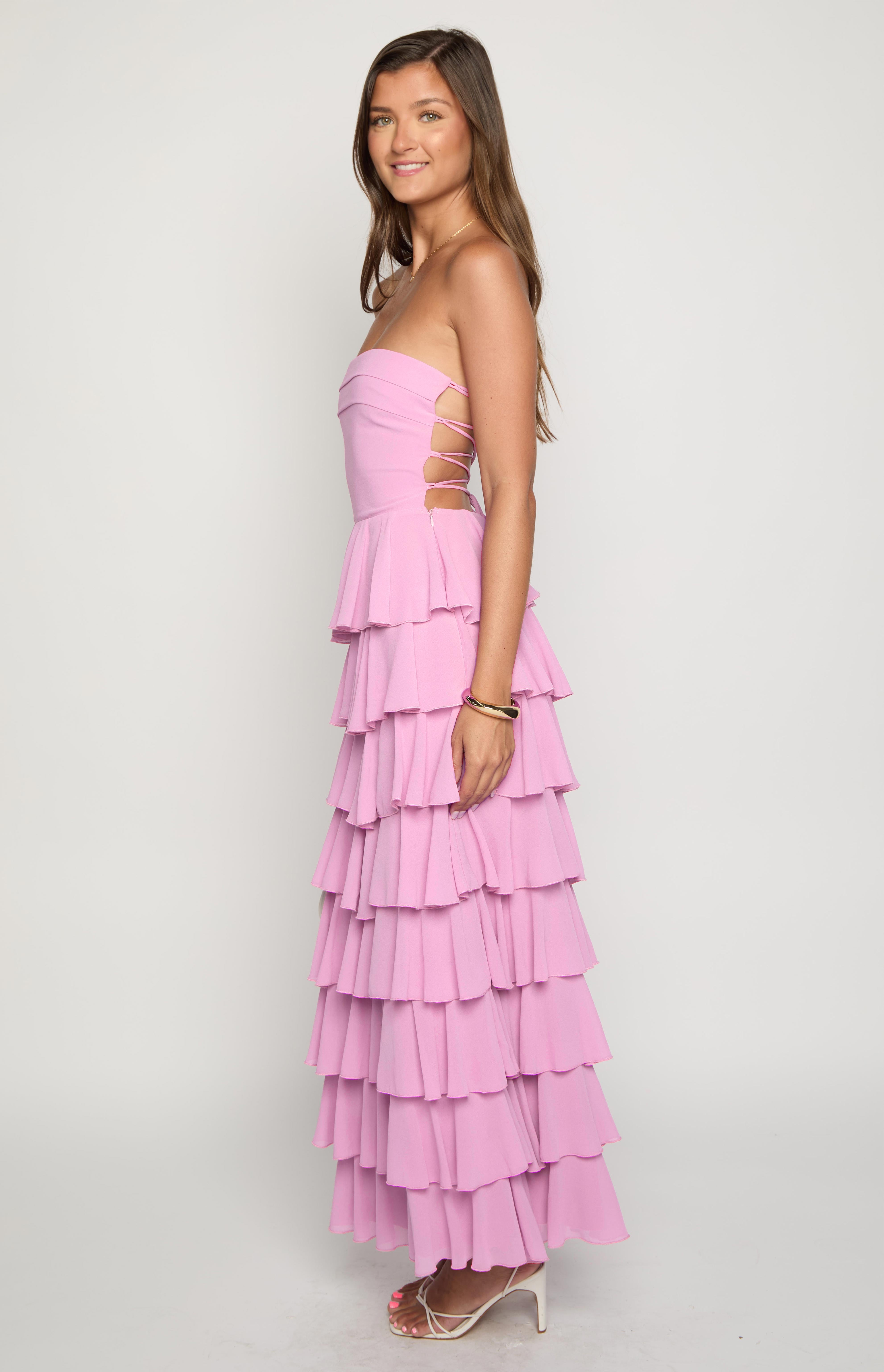 Side view of a pink strapless maxi dress with lace-up side cutouts and tiered ruffles