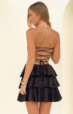 Rear view of a black strapless mini dress showing the criss-cross lace-up back and tiered ruffle skirt
