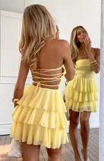 Back view of a yellow strapless mini dress with a criss-cross lace-up back and tiered ruffle skirt