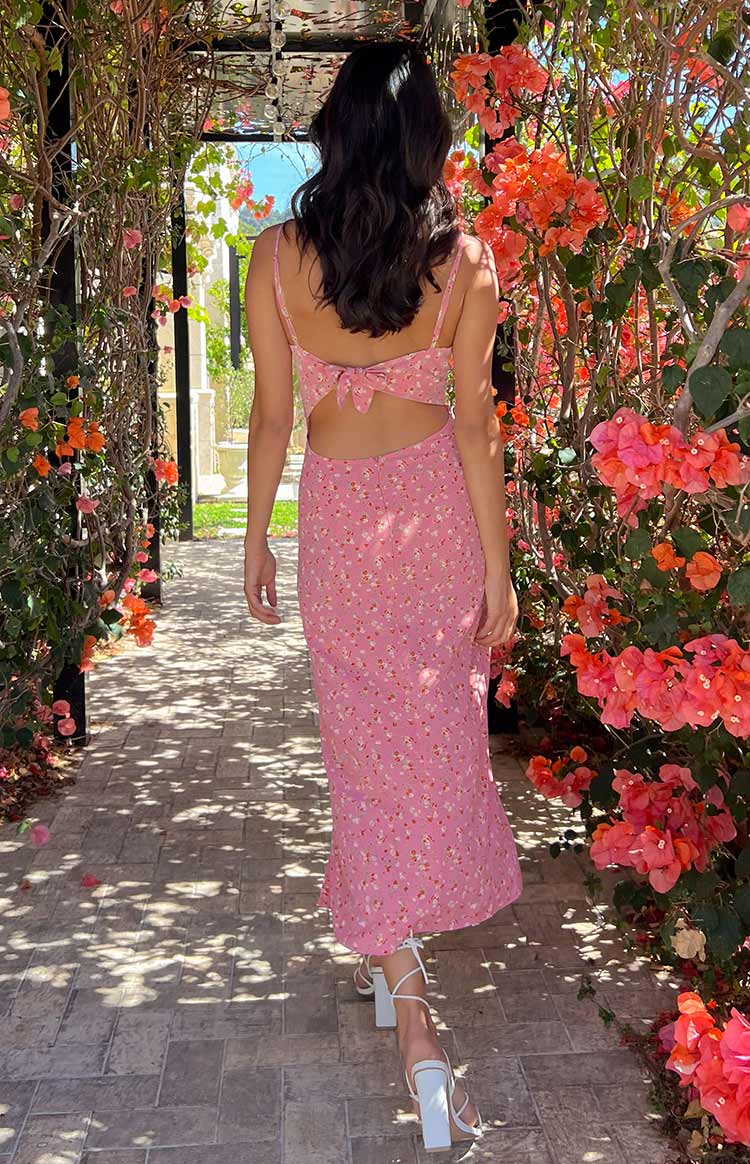 Rear view of a pink floral midi dress with a back tie detail and waist cutout