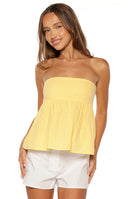 Close up of a pale yellow strapless babydoll top styled with denim shorts for a casual Summer look