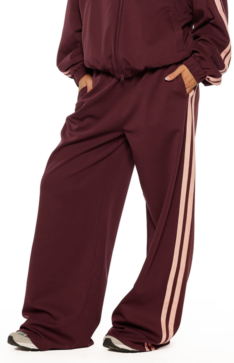 Beginning Boutique Kosie Burgundy and Pink Stripe Track Pants — burgundy wide-leg track pants with pink side stripes and elasticated waist