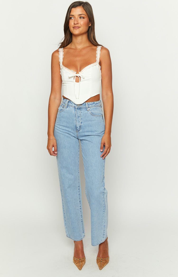 White corset top with delicate lace trim on the straps and sweetheart neckline, featuring a tie-front detail and pointed hem