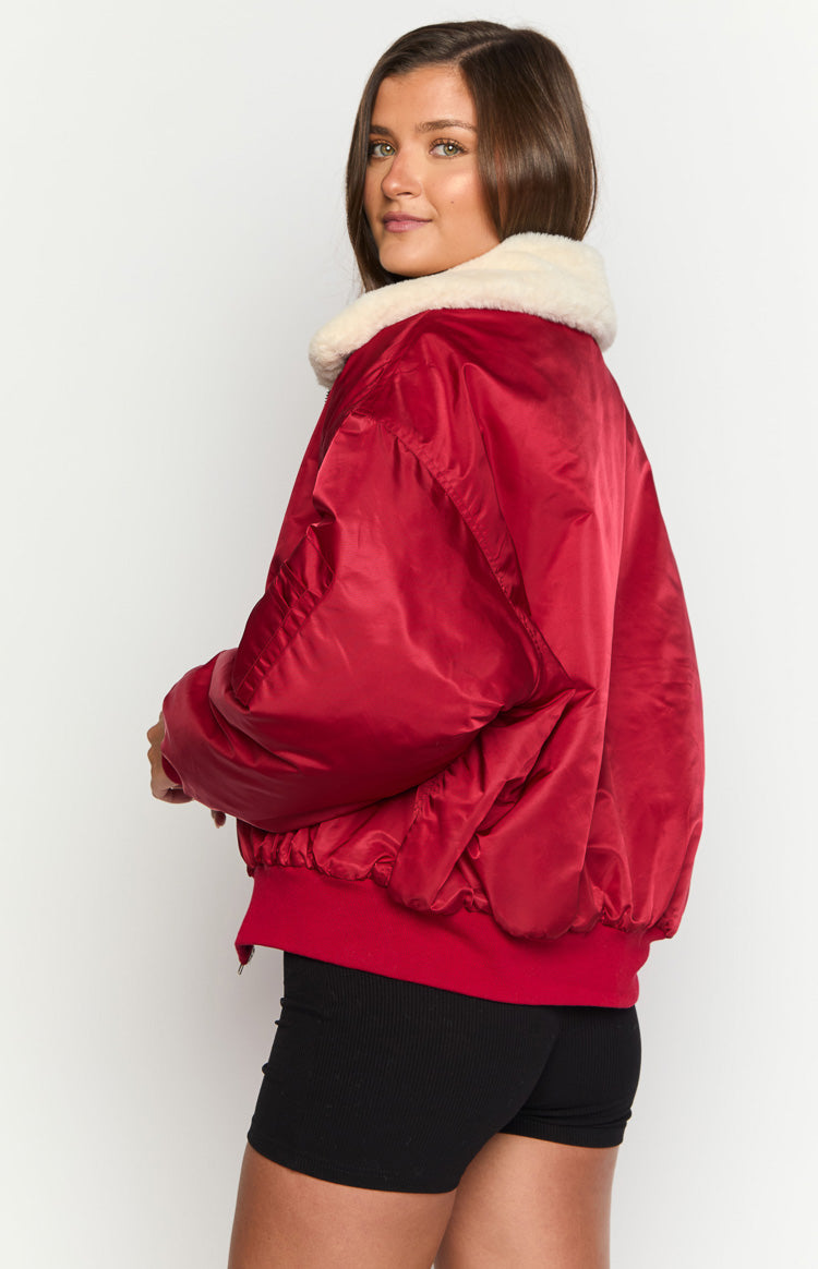Side view of a red puffer jacket with a cream faux fur collar and ribbed hem