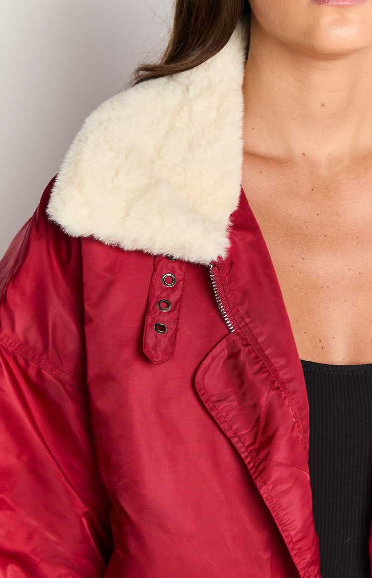 Close-up of the cream faux fur collar, silver zipper, and eyelet detail on a red puffer jacket