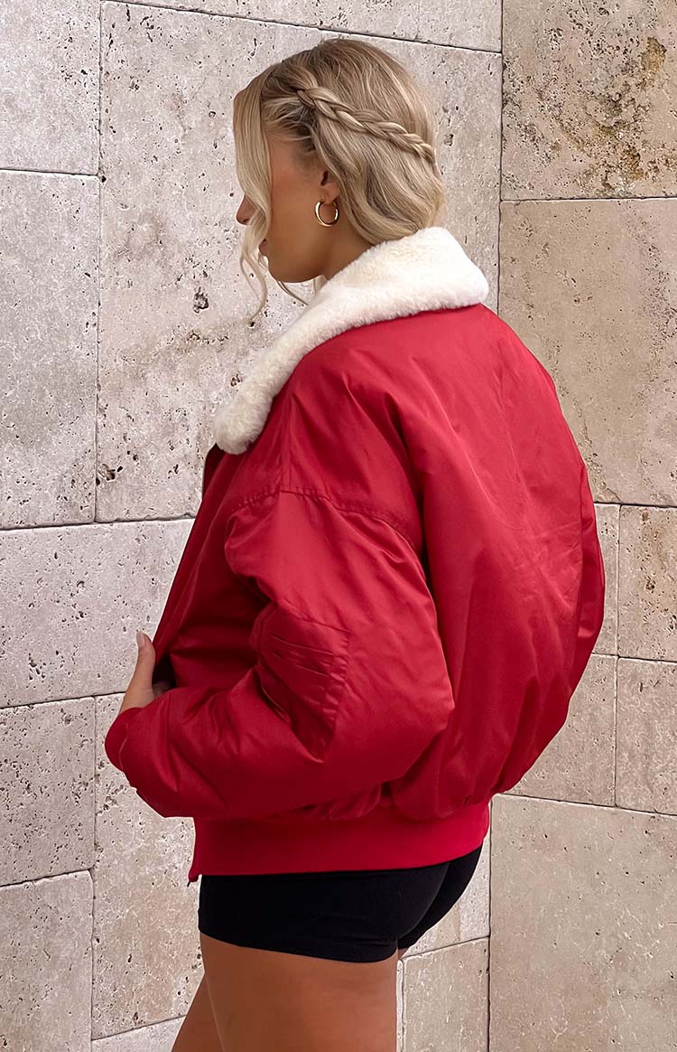 Side view of a red puffer jacket with a white faux fur collar and ribbed hem