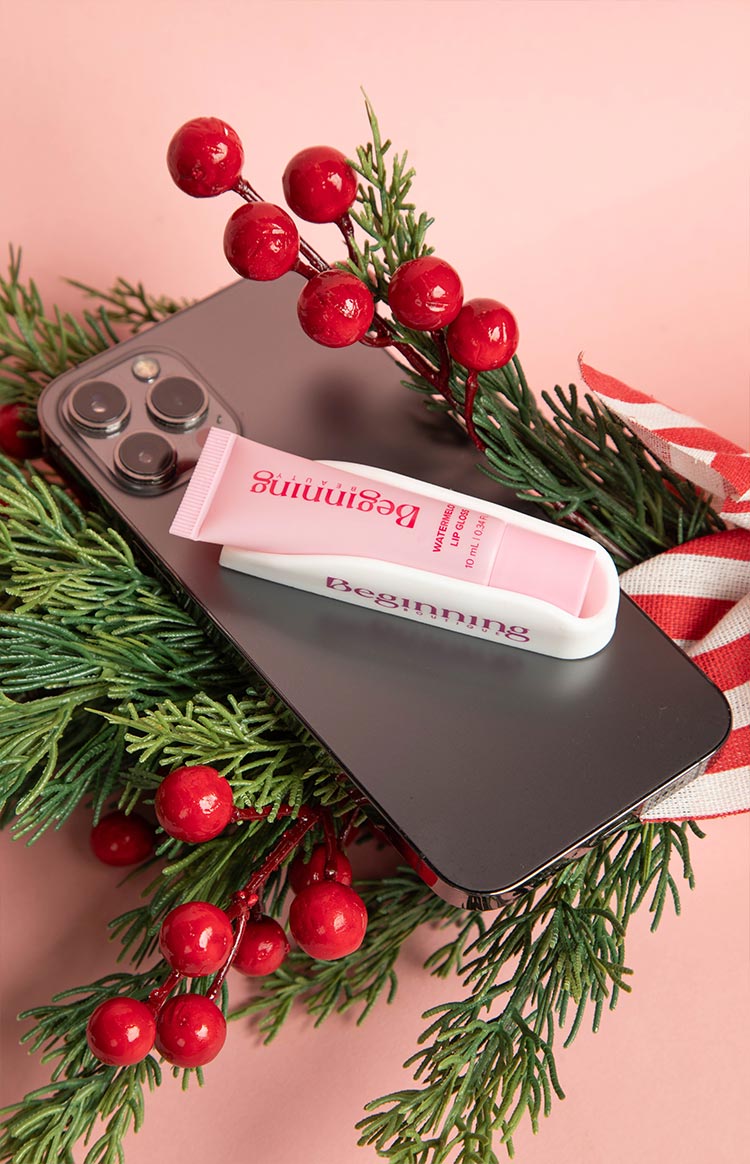 White phone holder with a pink lip gloss tube nestled in its curved slot