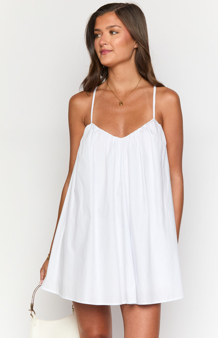 Front view of a white mini dress with gathered sweetheart neckline, thin spaghetti straps, and loose babydoll fit