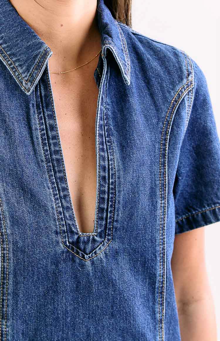 Close-up of the collared neckline with a deep V-placket and contrast stitching on a dark wash denim mini dress
