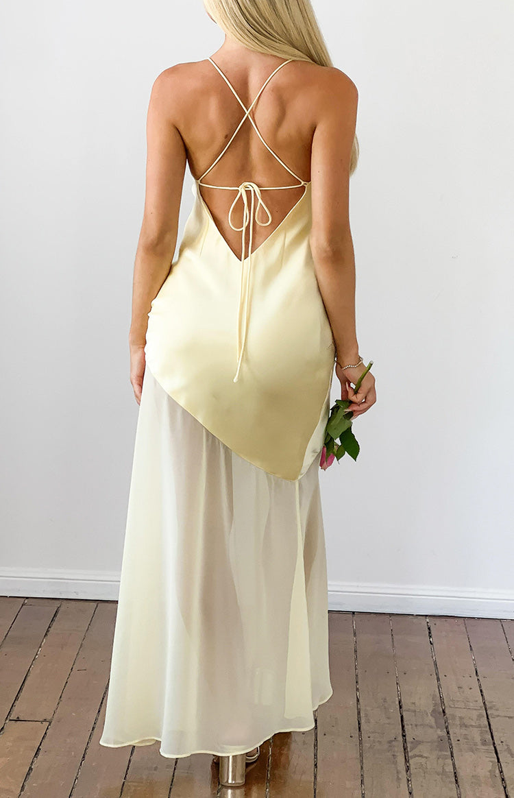 Rear view of a yellow satin maxi dress with a low V-back, criss-cross spaghetti straps, and tie-back detail