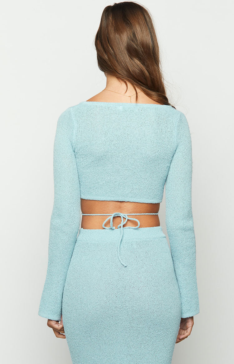 Rear view of a light blue long sleeve knit top with a wide square back neckline, cropped hem, and tie-back waist