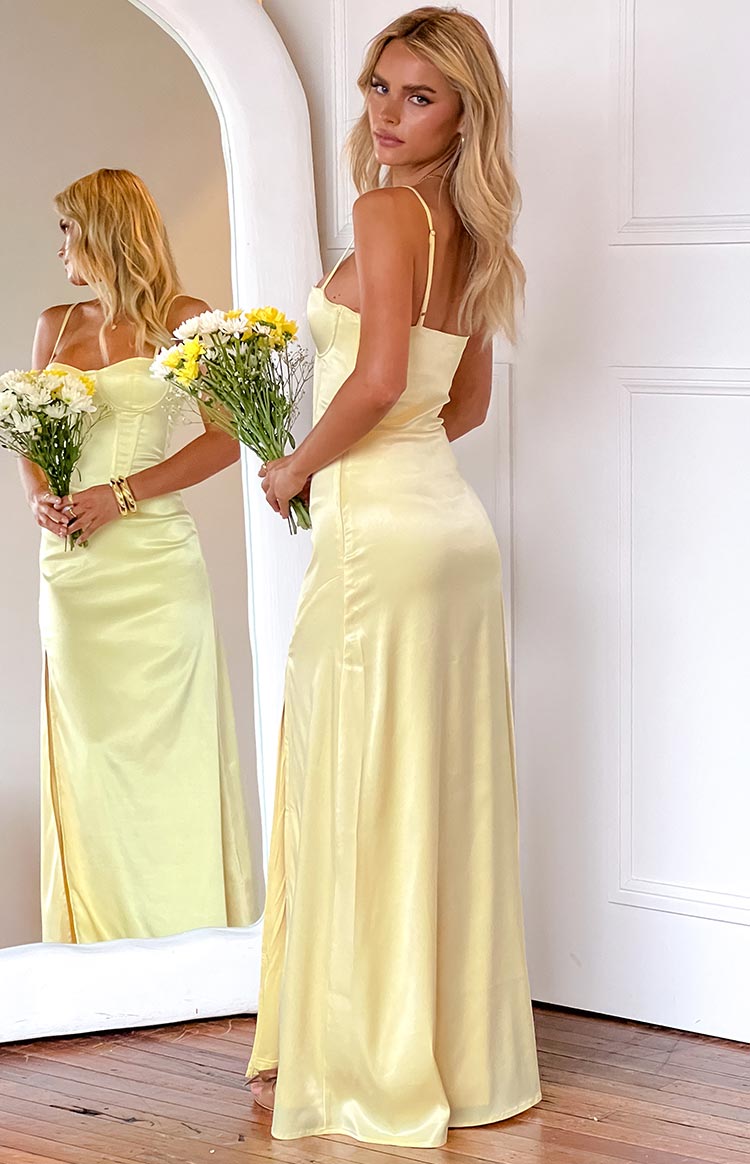 Side view of a yellow satin maxi dress with spaghetti straps and a flowing skirt with a high side slit
