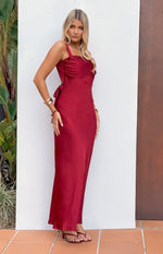Side view of a wine satin maxi dress with a square neckline, ruched bust, side cutouts, and waist ties