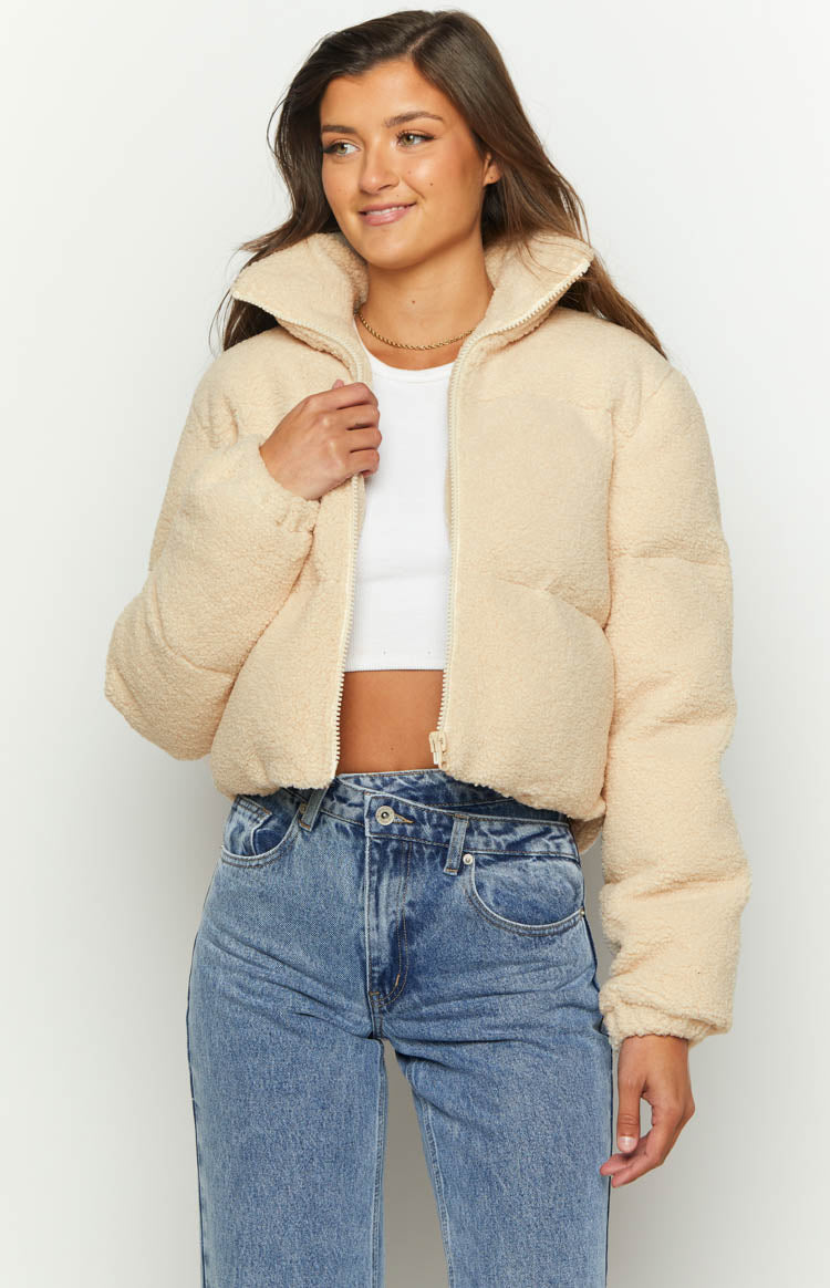 Beige teddy puffer jacket with a high stand collar, textured fabric, and partially unzipped front