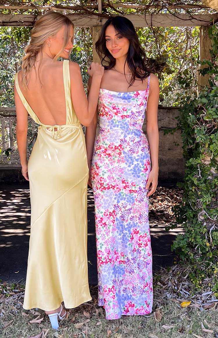 Vibrant pink, purple, and red floral print on a white fitted maxi dress with a cowl neck and spaghetti straps