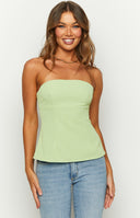 Our model wearing a fitted strapless top in a light green color. The top features a straight neckline and structured vertical seaming down the bust and bodice with a subtle peplum or slight flare at the hip ending in a curved hemline.