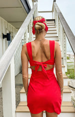 Rear view of a red mini dress with a large tie-back detail and side cutouts at the waist