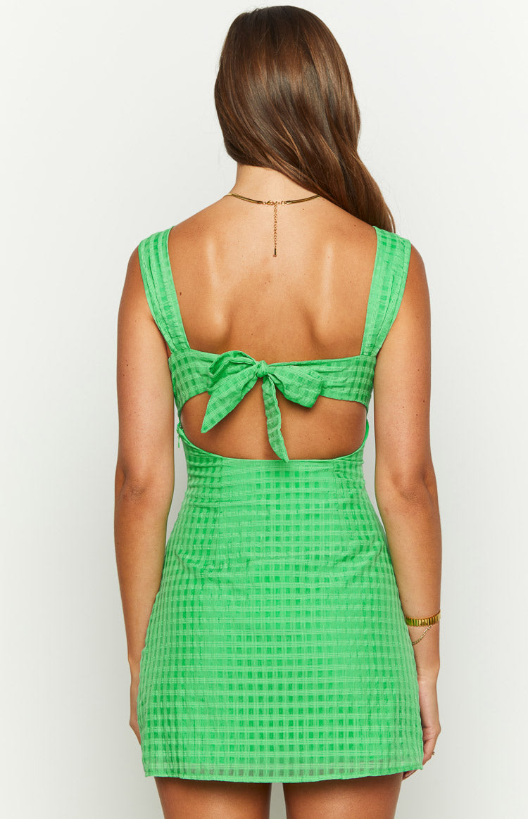 Rear view of a green mini dress with a subtle textured check pattern, featuring a tie-back and waist cutouts