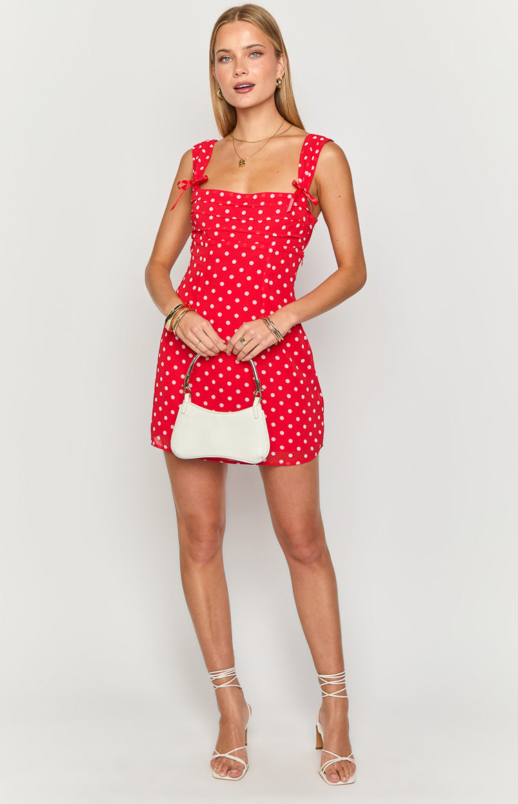 Red polka dot mini dress with a square neckline, ruched bodice, and shoulder straps tied into bows
