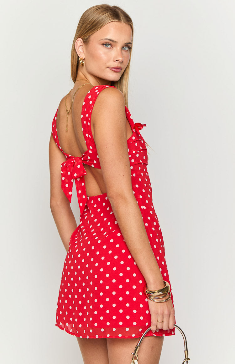 Rear-side view of a red polka dot mini dress showing the large tie-back bow and open back cutouts