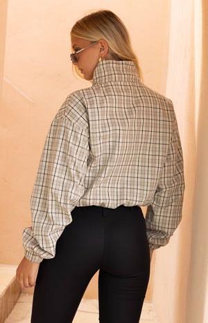 Rear-side view of the beige plaid funnel neck jacket, featuring a high collar and relaxed voluminous sleeves