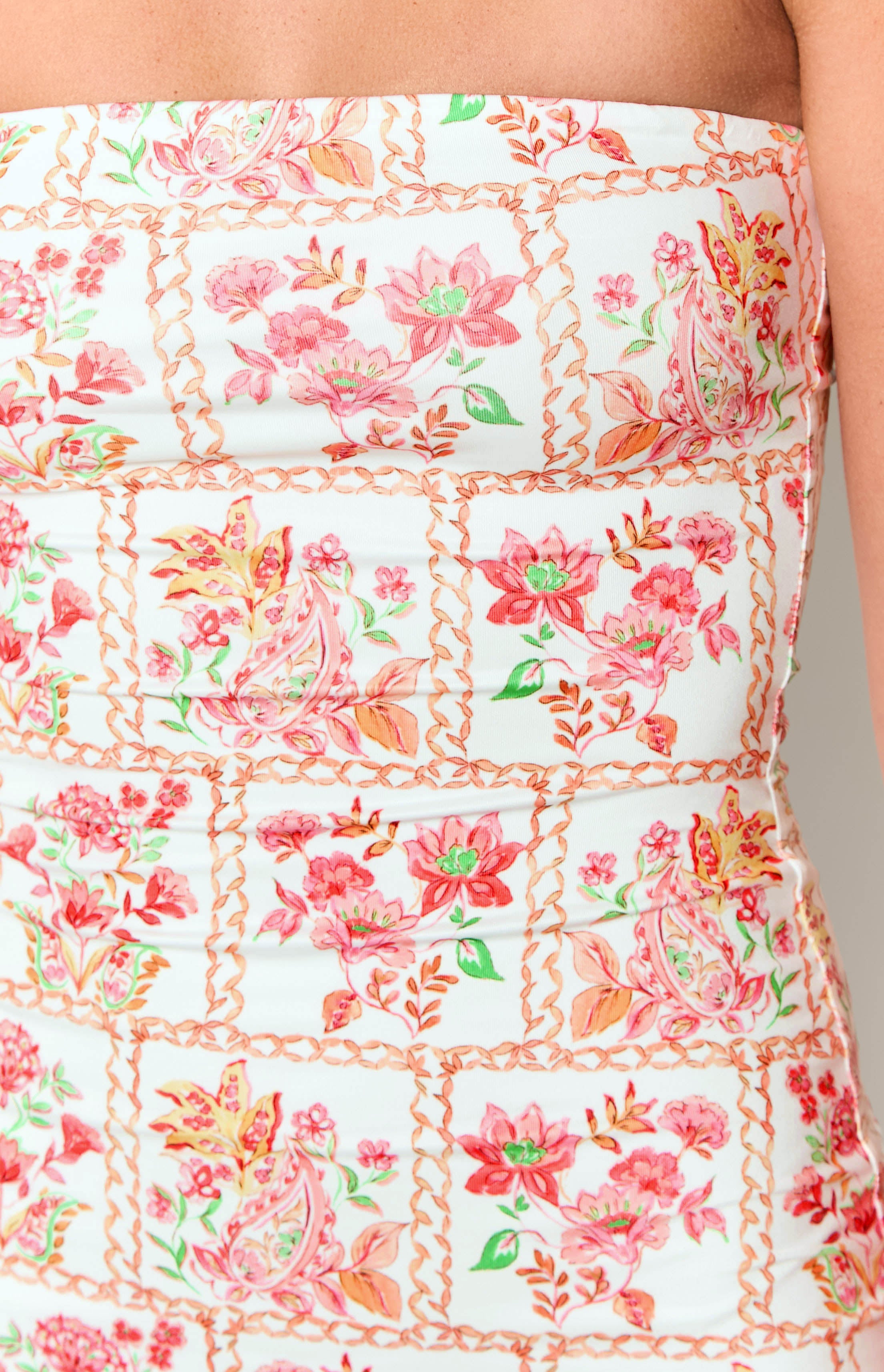 Close-up of the white fabric with pink and orange paisley floral print, chain borders, and horizontal ruching