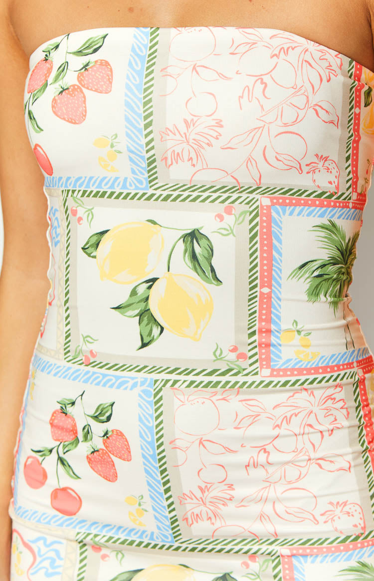 Close-up of the white mini dress showing the patchwork print with lemons, strawberries, cherries, and palm leaves