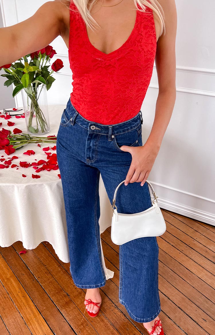 Front view of dark blue denim flare jeans showing the waistband, button closure, and wide leg