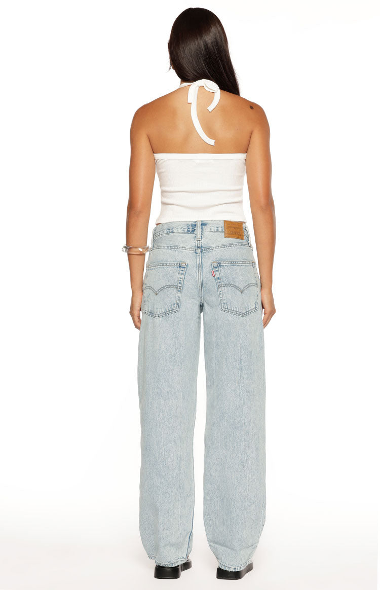 Rear view of light wash baggy dad jeans showing the leather brand patch and classic back pocket stitching