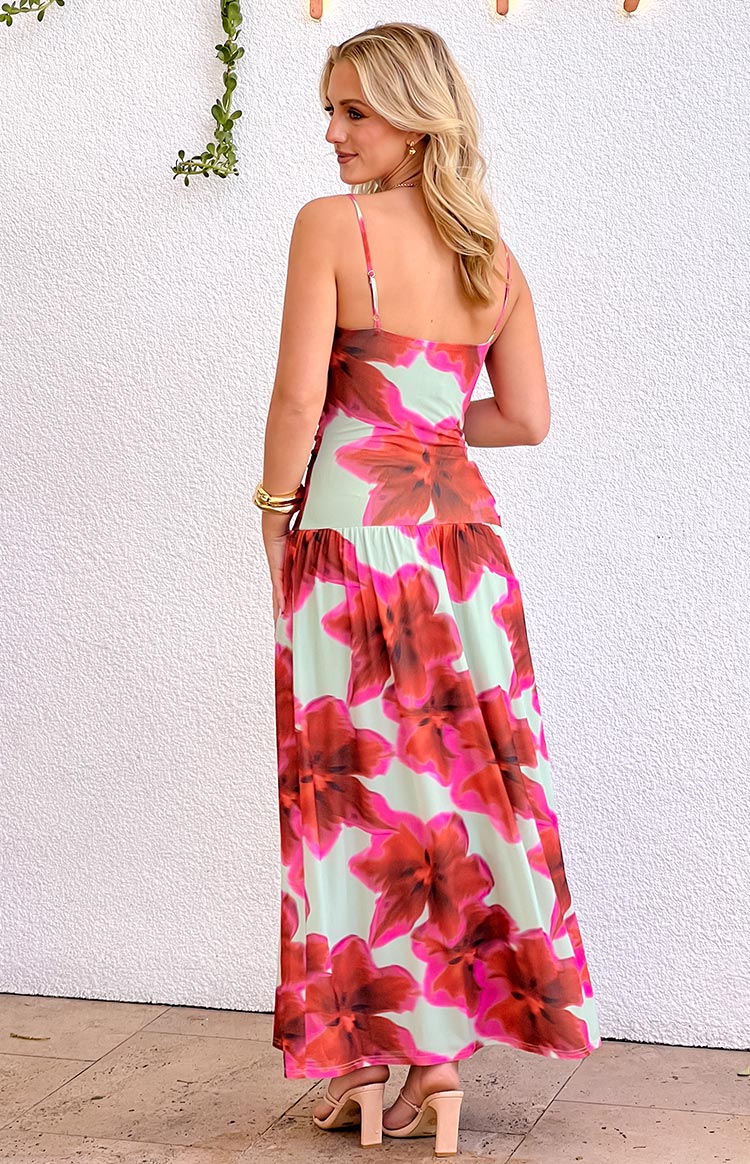 Rear-side view of a green maxi dress with large pink floral print, thin spaghetti straps, and a dropped gathered waist