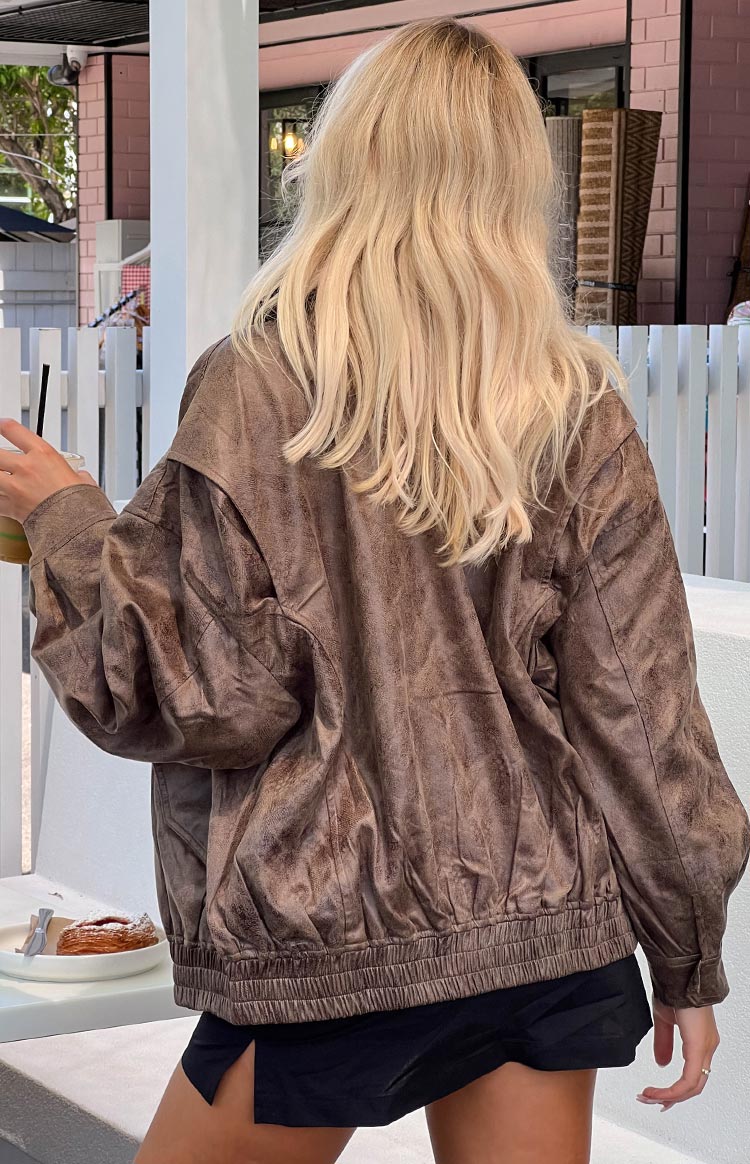 Rear view of a chocolate distressed bomber jacket with an elasticated hem and voluminous gathered sleeves