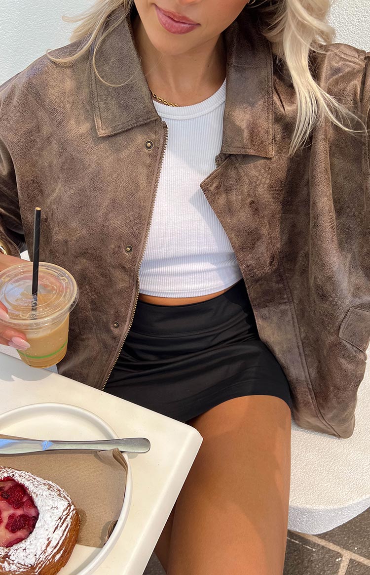 Close-up of the chocolate distressed bomber jacket, partially unzipped, showing the textured fabric and collar