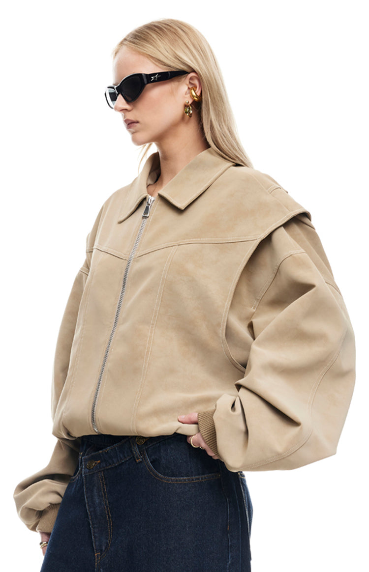 Side view of a latte bomber jacket showing the pointed collar, silver zipper, and layered shoulder detail