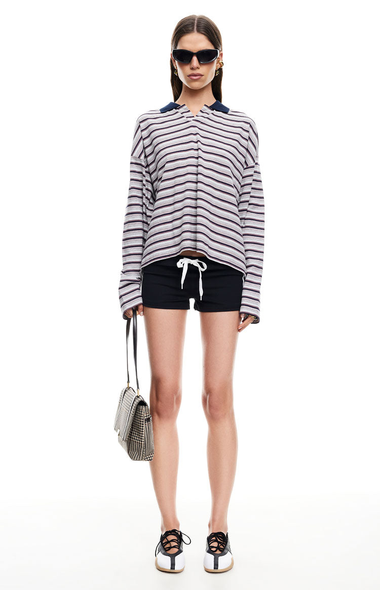 Front view of a grey and black stripe long sleeve jersey top with a navy polo collar and relaxed, slightly cropped fit