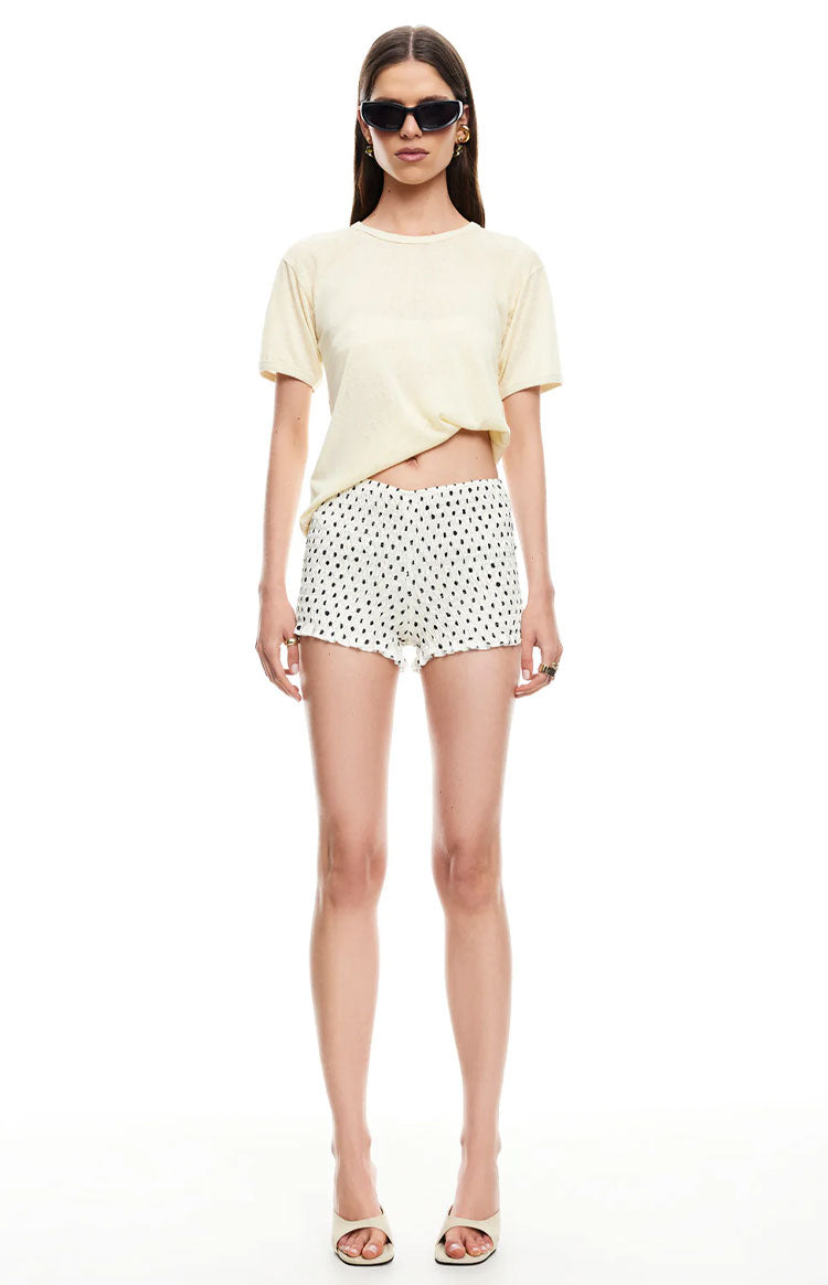 Front view of white mini shorts with black polka dots and an elasticated waist
