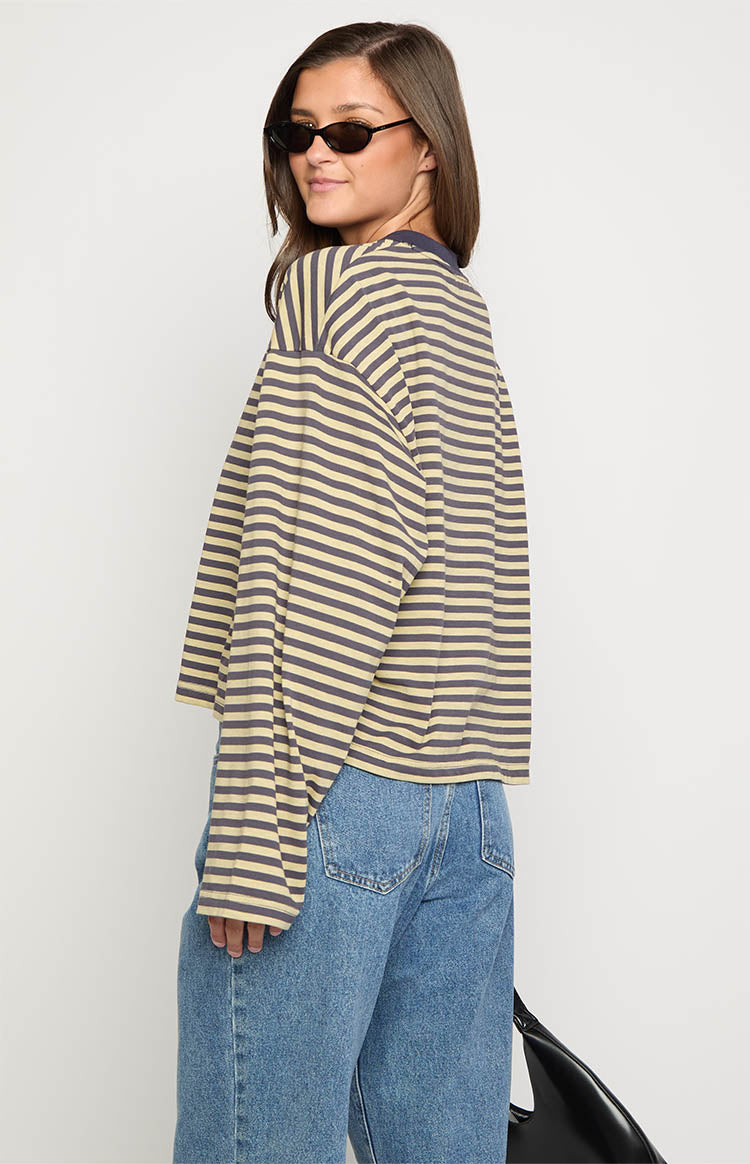 Side view of a beige and dark striped long sleeve top with a relaxed fit and a dark polo collar