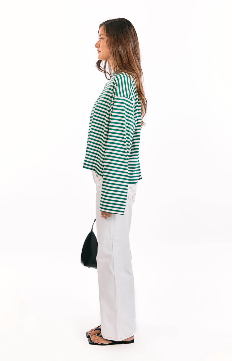 Side view showing the relaxed fit and long sleeves of a moss green and white striped top