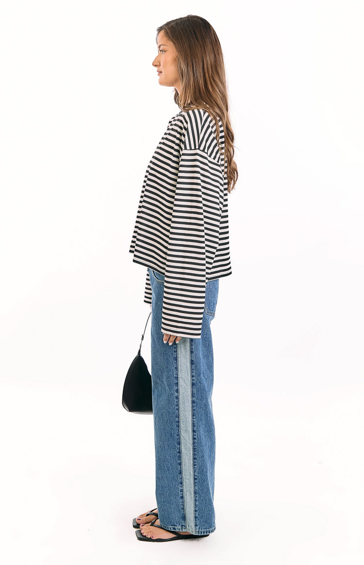 Side profile of the black and white striped long sleeve top, highlighting its relaxed, cropped fit