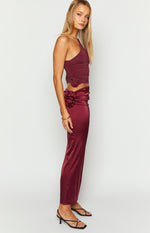 Side view of a burgundy satin maxi skirt with a rosette detail on the hip