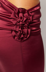 Close-up of two burgundy satin fabric rosettes with ruched detailing on a maxi skirt