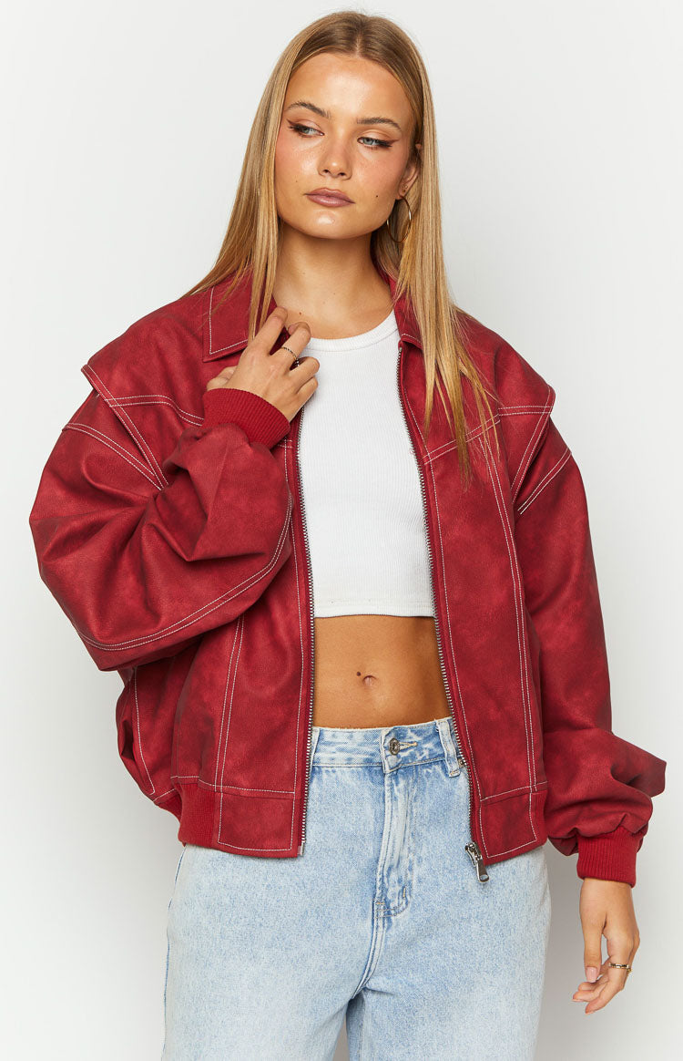 Close-up of the crimson bomber jacket showing the textured fabric, white contrast stitching, and ribbed cuffs