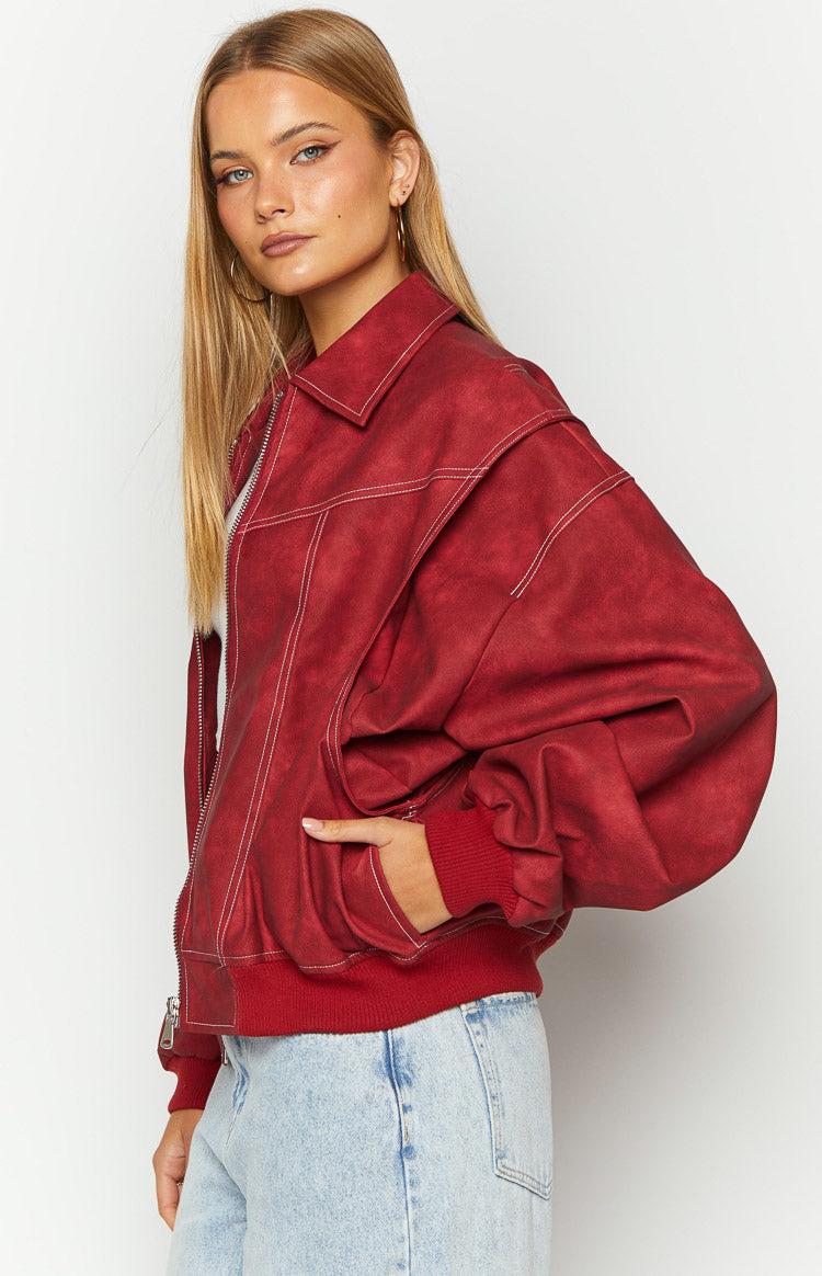 Side view of a crimson bomber jacket with white contrast stitching, dropped shoulders, and voluminous sleeves