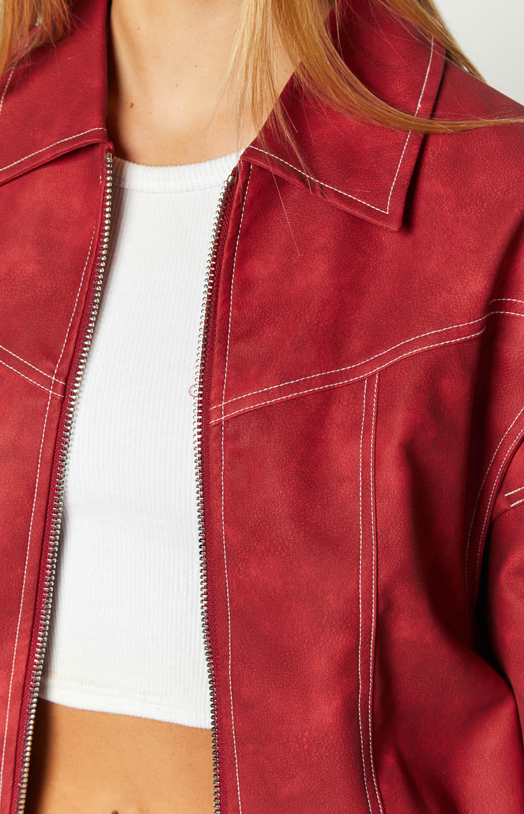 Close-up of the crimson bomber jacket showing the textured fabric, white contrast stitching, and silver zipper