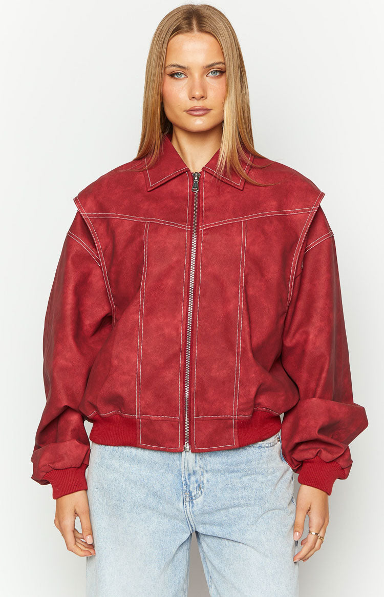 Close-up of a crimson bomber jacket featuring white contrast stitching, a structured collar, and silver zip